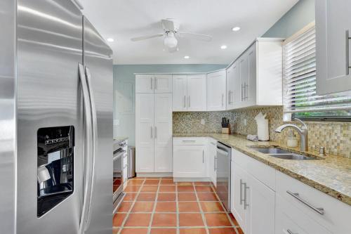 a kitchen with white cabinets and a stainless steel refrigerator at Subtropical Oasis -Naples Fl Retreat in Naples