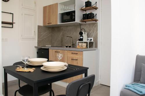 uma pequena cozinha com uma mesa preta e cadeiras em Au Pied du Vieux-Port Wifi Netflix em Marselha