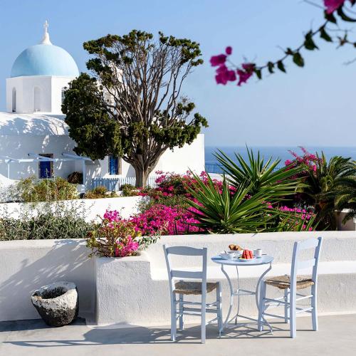 a table and two chairs and a table and some flowers at Aghios Artemios Traditional Houses in Imerovigli