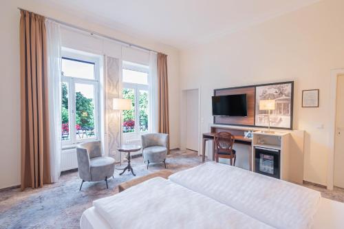 um quarto de hotel com uma cama, uma secretária e uma televisão em Hotel Villa am Kurpark em Bad Homburg vor der Höhe