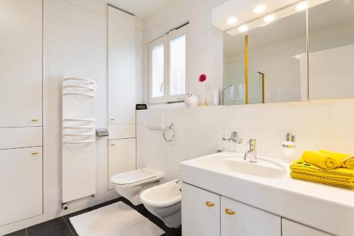 a white bathroom with a sink and a toilet at Sonnenschein in Brione sopra Minusio