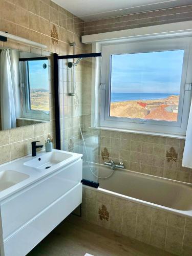 a bathroom with a sink and a tub and a window at Koksijde Zeedijk Res Manh in Koksijde