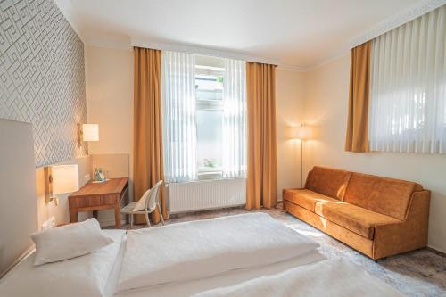 a hotel room with a bed and a couch at Hotel Villa am Kurpark in Bad Homburg vor der Höhe