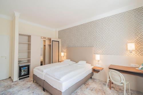 a hotel room with a bed and a desk and a table and chair at Hotel Villa am Kurpark in Bad Homburg vor der Höhe