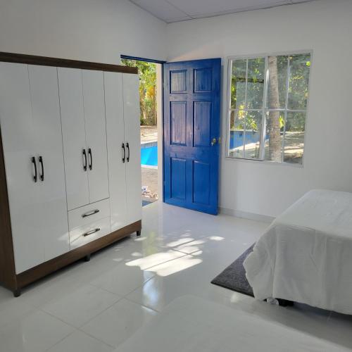 1 dormitorio con 1 cama y puerta azul en RANCHO SARIMAR, en La Libertad