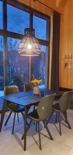 een eettafel met stoelen en een kroonluchter bij Odenwald-Lodge mit Infrarotsauna und E-Ladestation "Haus Purpur" in Reichelsheim