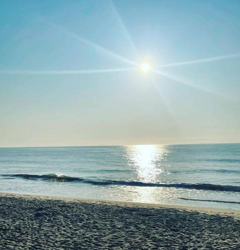 a beach with the sun rising over the ocean at The Grenville Hotel and Restaurant in Bay Head