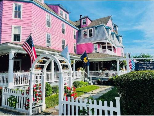 una casa rosa con una cerca blanca delante de ella en The Grenville Hotel and Restaurant, en Bay Head