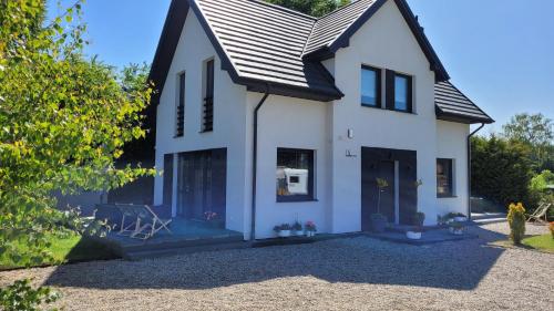 een wit huis met een zwart dak bij DĘBKI DOMKI SASANKOWE in Dębki