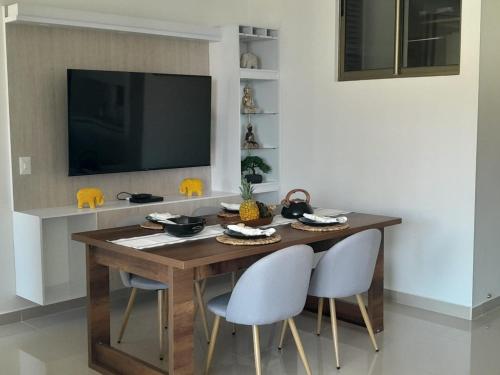 a dining room table with two chairs and a television at Increible apartamento Samaria Club de Playa, Santa Marta, Pozos colorados in Gaira