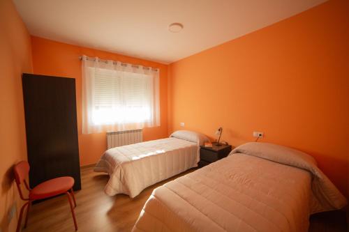 2 camas en una habitación con paredes de color naranja en Casa Galetxo, junto a Bardenas Reales y Sendaviva en Valtierra