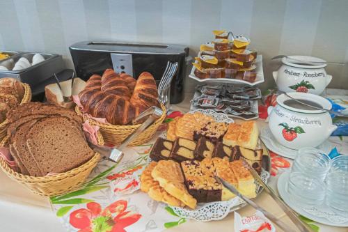 a table topped with different types of bread and pastries at Hotel Villa am Kurpark in Bad Homburg vor der Höhe