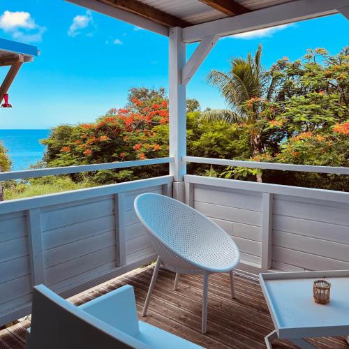 a balcony with a table and chairs and the ocean at Kaz 4 plages - Accès plages & Vue Mer in Deshaies