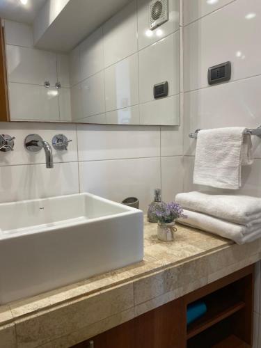 uma casa de banho branca com um lavatório e toalhas num balcão em Departamento en el corazón de Providencia em Santiago