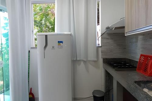 a white refrigerator in a kitchen with a window at Flats Nascer do Sol in Cayru