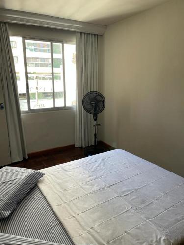 um quarto com uma cama e uma janela com uma ventoinha em FAROL DA BARRA 2/QUARTOS em Salvador