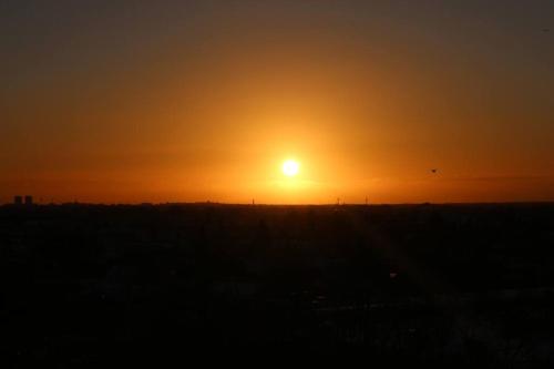 zachód słońca nad polem ze słońcem na niebie w obiekcie Lille nest w mieście Rødovre