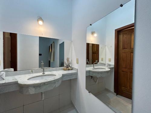 a bathroom with two sinks and a large mirror at Morada Pedra da Lua in Porto Seguro