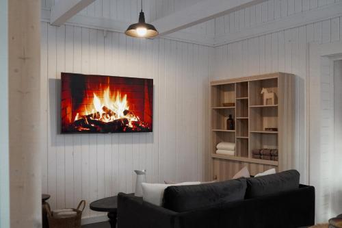 a living room with a couch and a fire on the wall at Pieprz & Sól FARMHOUSES in Załuczne