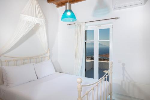 a white bedroom with a bed and a window at Aegean Stones in Agios Ioannis Mykonos