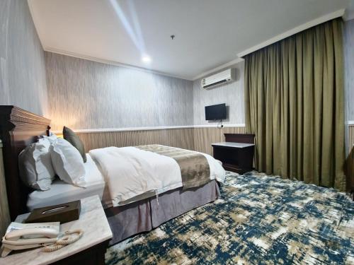 a hotel room with a bed and a phone in it at قصور الشرق للاجنحة الفندقية Qosor Al Sharq in Jeddah