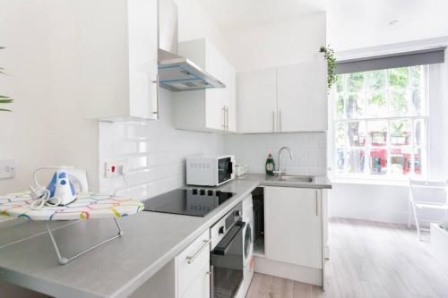 a white kitchen with a counter and a sink at Beautiful Studio Flat in Hackney next to Overground Station in London