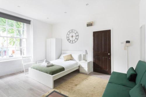 Habitación blanca con cama y sofá en Beautiful Studio Flat in Hackney next to Overground Station en Londres
