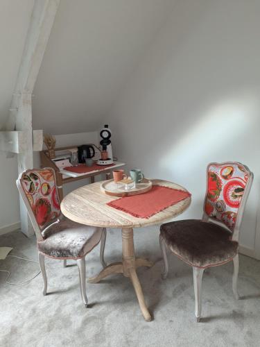 une table avec deux chaises et une table avec une plaque de cuisson dans l'établissement La chambre Mademoiselle Causeuse, à Malville