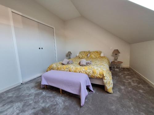 a bedroom with a large bed with a purple blanket at La chambre Mademoiselle Causeuse in Malville