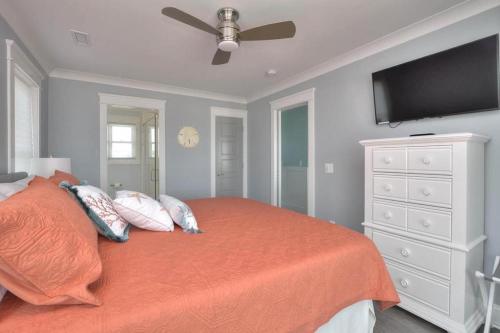 a bedroom with a bed with an orange blanket and a tv at Latitude Adjustment in Oak Island
