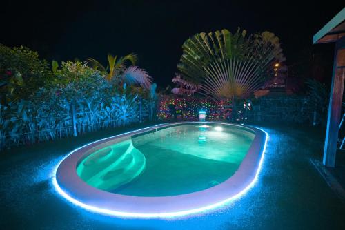 uma piscina com luzes azuis num quintal à noite em Au cœur du papillon piscine privée em Goyave