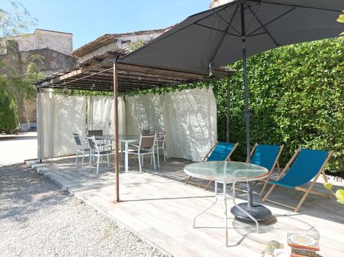 un patio con mesa, sillas y sombrilla en Chez Sonia, en Sarrians