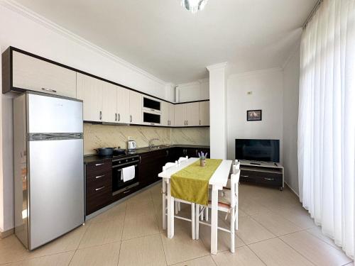 a kitchen with a table with chairs and a refrigerator at Parid Appartments in Sarandë