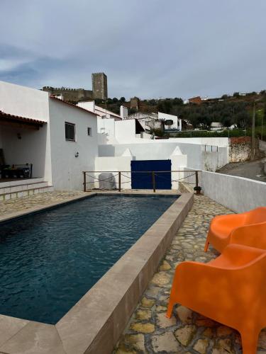 a swimming pool with orange chairs next to a house at Cantinho da Villa in Portel