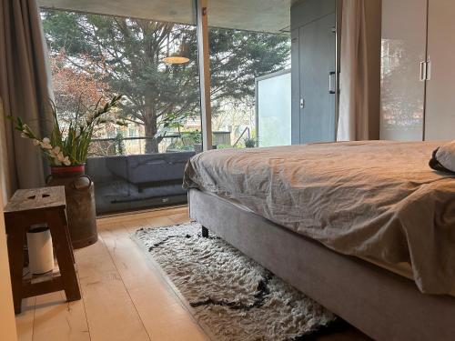 um quarto com uma cama e uma grande janela em Homestay Properties em Amesterdão