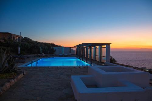 a swimming pool with a sunset in the background at Aegean Stones in Agios Ioannis Mykonos