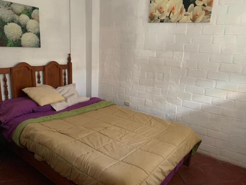 1 dormitorio con 1 cama y pared de ladrillo blanco en Casa amarilla PH depa 2dorm 3er piso, en Punta Hermosa