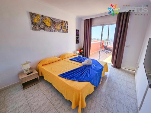a bedroom with a large bed with a blue blanket at 7Lizards - Ocean View Apartments in Puerto de Santiago