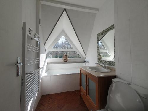 La salle de bains est pourvue d'une fenêtre triangulaire et d'un lavabo. dans l'établissement Gîte du parc - VALLOIRE SUR CISSE, à Seillac