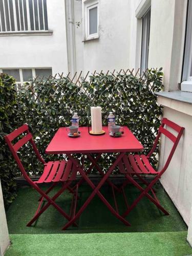 une table rouge et deux chaises sur la terrasse dans l'établissement Charmant studio Paris 17ème, à Paris