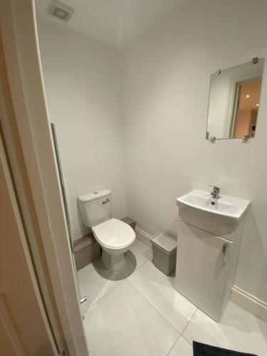 biała łazienka z toaletą i umywalką w obiekcie 15 min to Central London Guest Suites 22 w Londynie