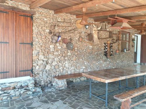 Habitación con pared de piedra y mesa de madera. en Azienda agricola Affittacamere S'Ispinalba di Laura Pitzolu, en Borore