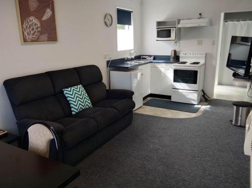 a living room with a couch and a kitchen at Queens Park Motels in Invercargill