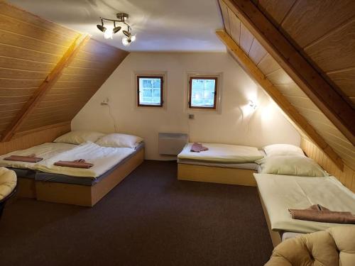 a attic room with two beds and two windows at Stylová roubená chalupa Jizerské hory in Kořenov
