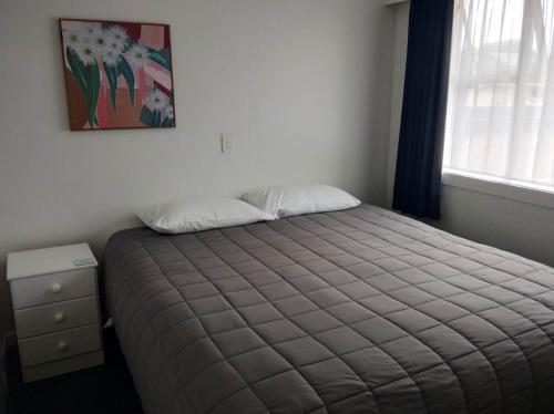 a bedroom with a bed and a window at Queens Park Motels in Invercargill