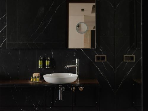 a black bathroom with a sink and a mirror at Grand Hotel in Łódź