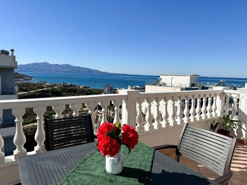 a table with red flowers on top of a balcony at Parid Appartments in Sarandë
