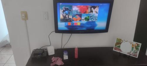 a tv on a wall with a table with a video game at Apartamento da Praia in Navegantes