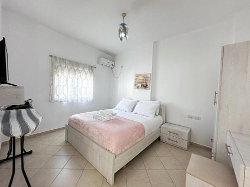 a white bedroom with a bed and a window at Parid Appartments in Sarandë