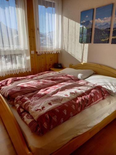 a bed with a red and white comforter on it at Le Perchoir in Gryon